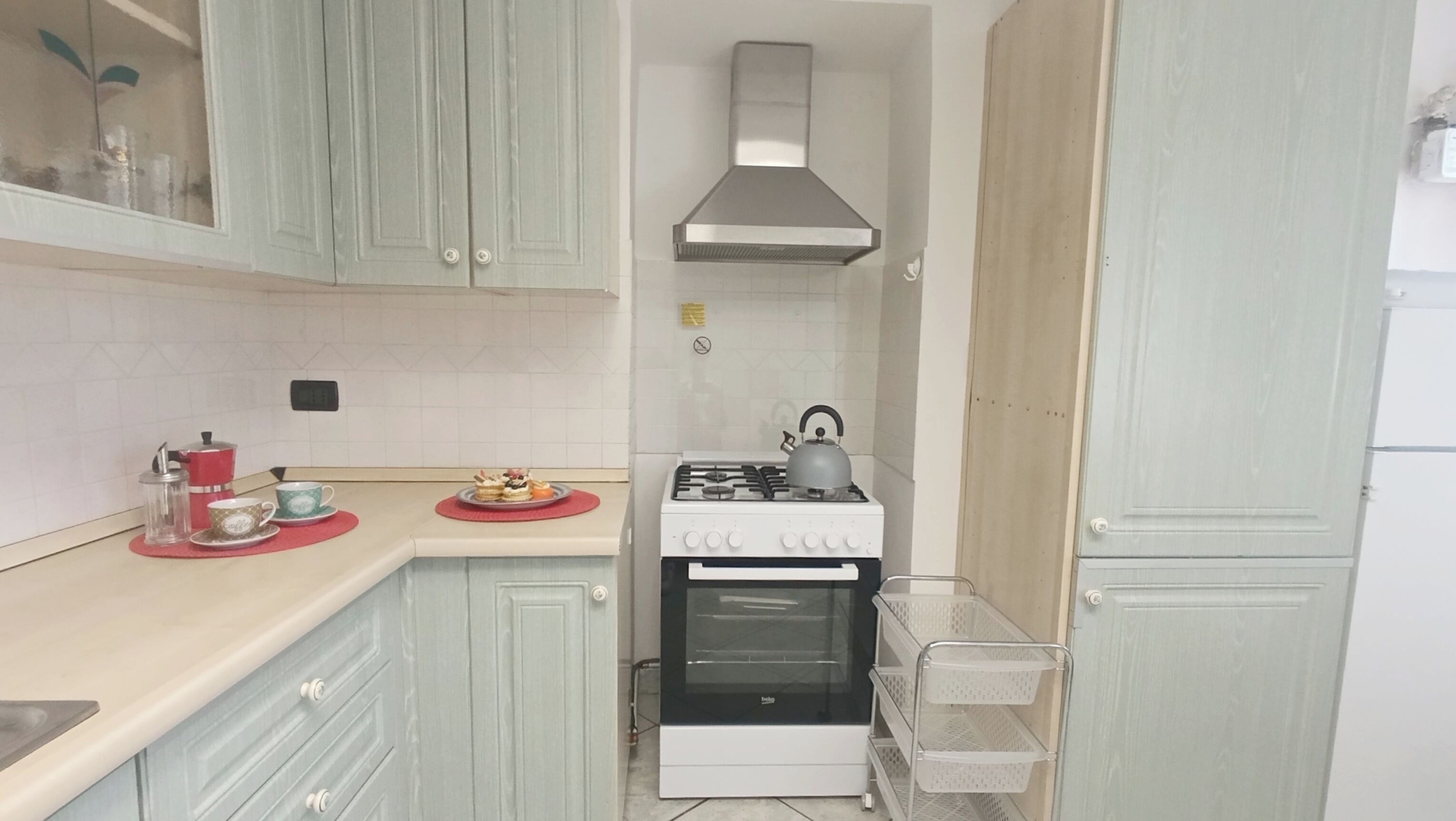 A compact kitchen with a gas stove, oven, and a stainless steel range hood.