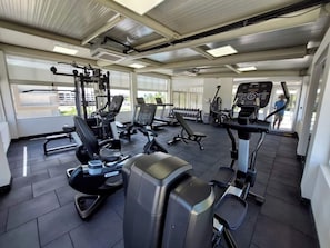 A gym with various exercise equipment, large windows, and a tiled floor. - Oceanfront 2BDR Penthouse with Jacuzzi at Playa Nueva Romana (San Pedro de Macorís)