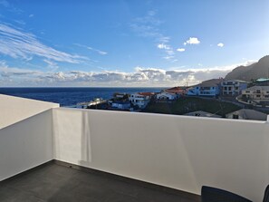 A balcony with a view of a coastal town and the sea.