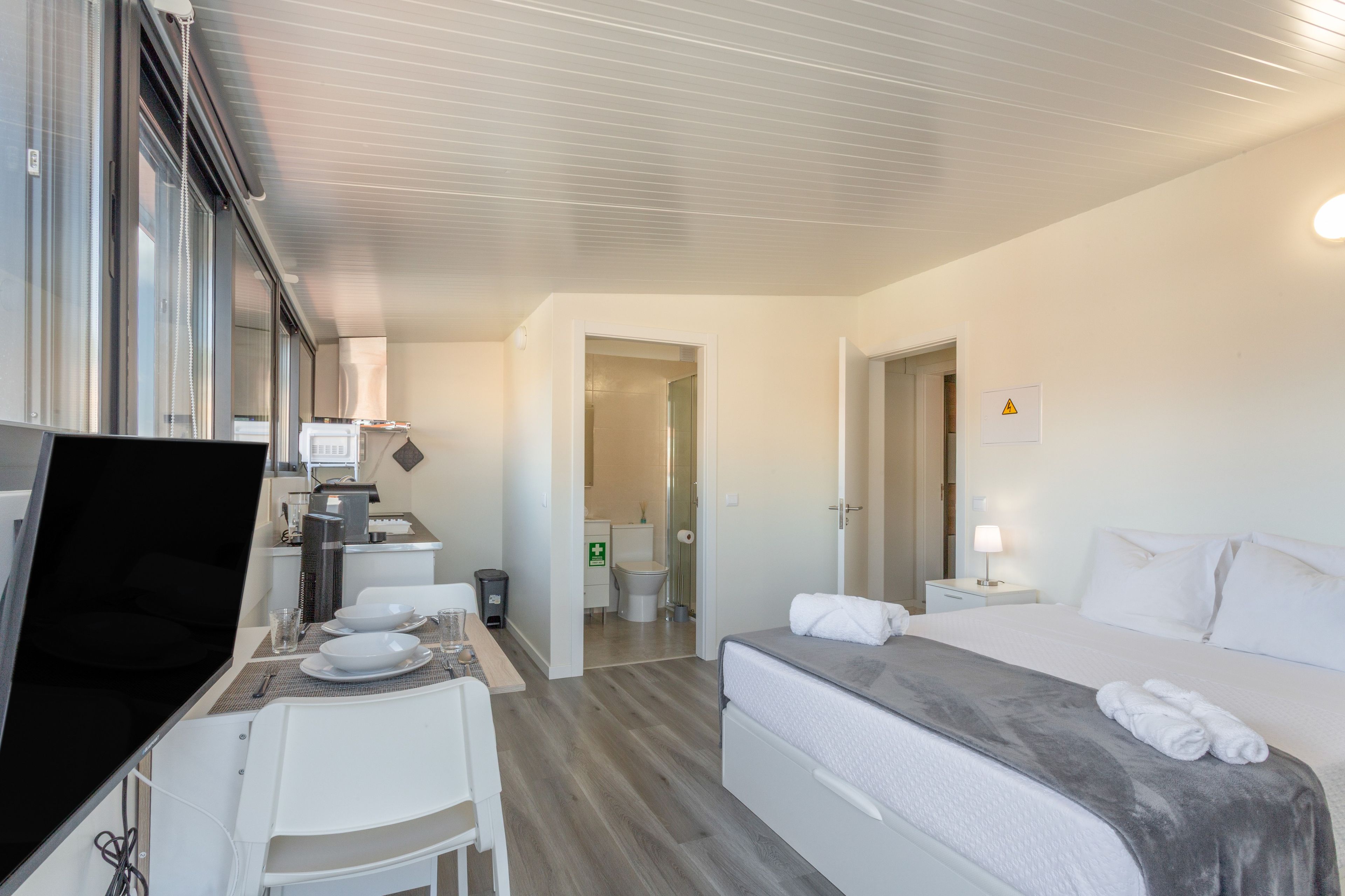 Une chambre d’hôtel comprenant un lit, un bureau avec une chaise, une petite kitchenette et une salle de bain.