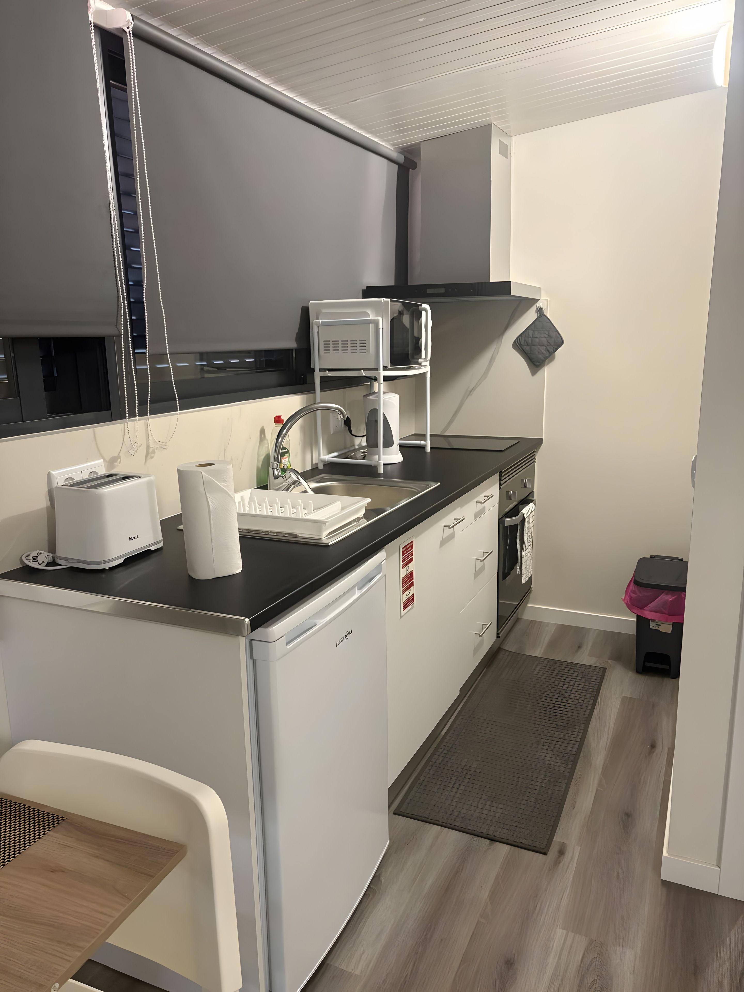 Cozinha compacta com micro-ondas, torradeira e pia.
