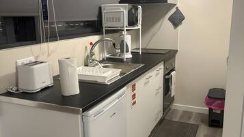 Cozinha compacta com micro-ondas, torradeira e pia.