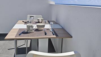 Una mesa de comedor con sillas en una terraza en la azotea, con vista despejada al cielo y al océano.