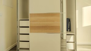 A walk-in closet with a sliding door, built-in drawers, and a hanging rod.
