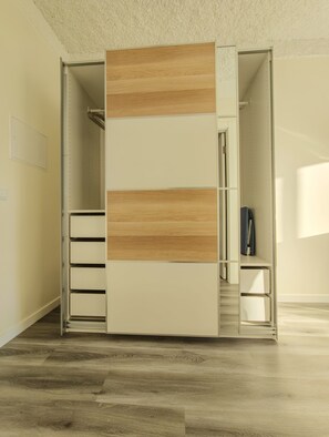 A walk-in closet with a sliding door, built-in drawers, and a hanging rod.