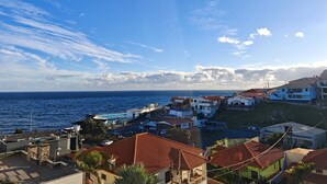 A coastal residential area with houses, a clear sky, and the sea in the background.