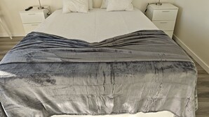 A bed with a grey blanket, two bedside tables with lamps, and a white headboard.