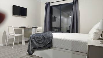 A modern hotel room with a bed, a desk, and a chair.