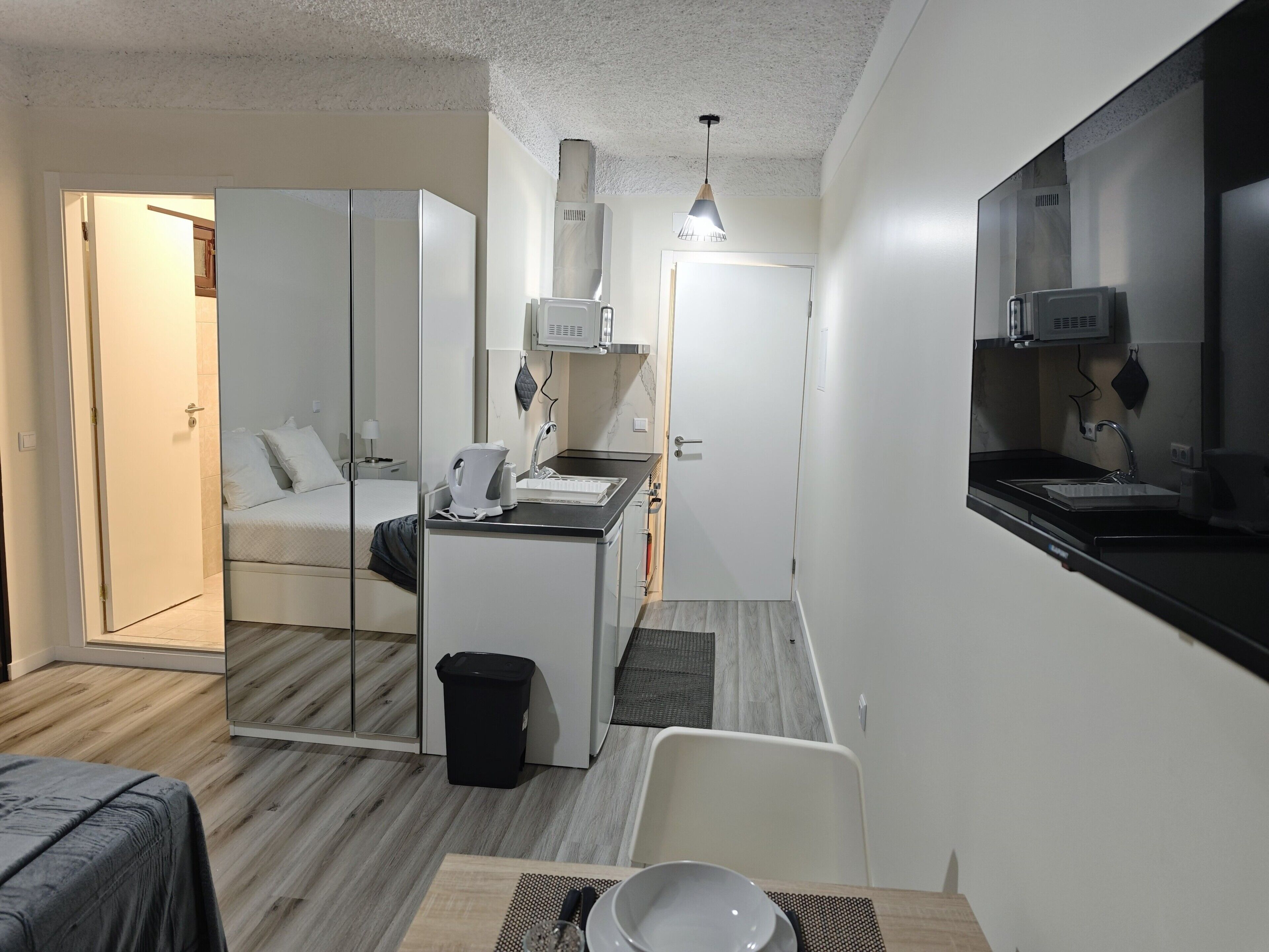 Habitación de hotel compacta con kitchenette, una cama y una pequeña zona de comedor.