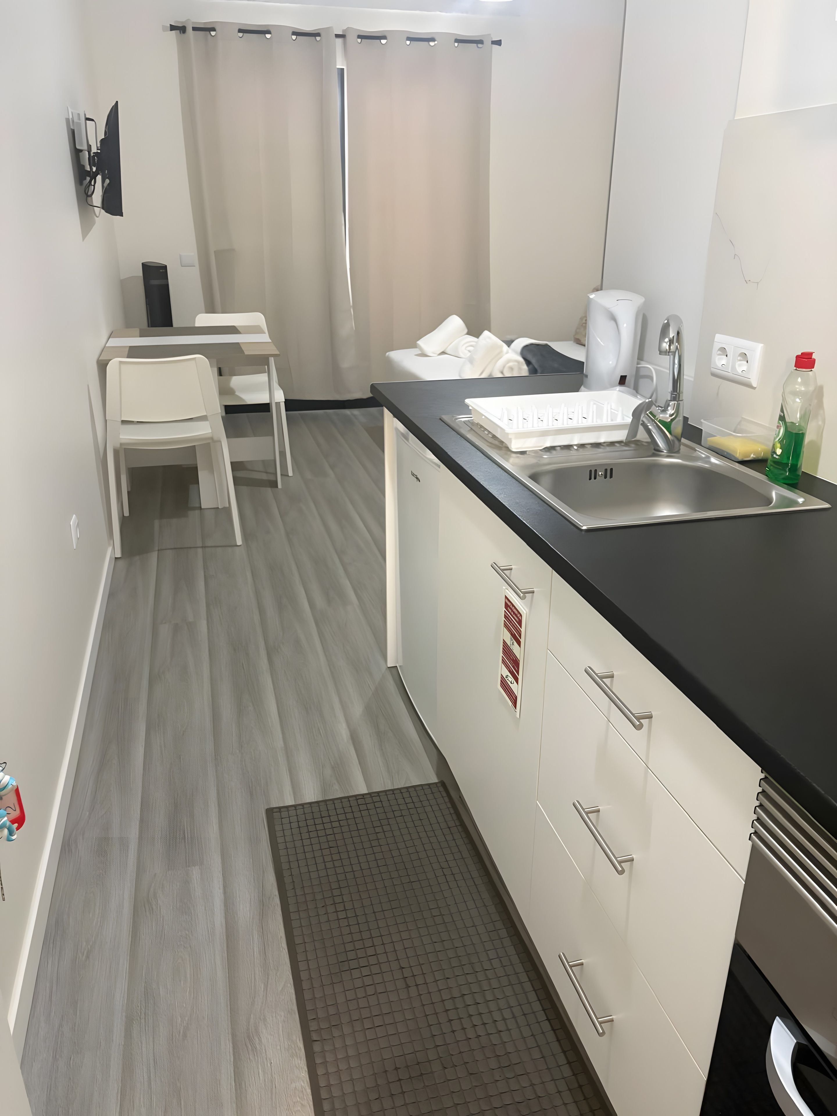 Una cucina compatta con lavandino, piano di lavoro e pensili bianchi.