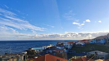 A coastal residential area with houses, a clear sky, and the sea in the background.