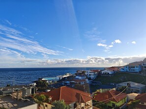 Una zona residencial costera con casas, cielo despejado y el mar al fondo.