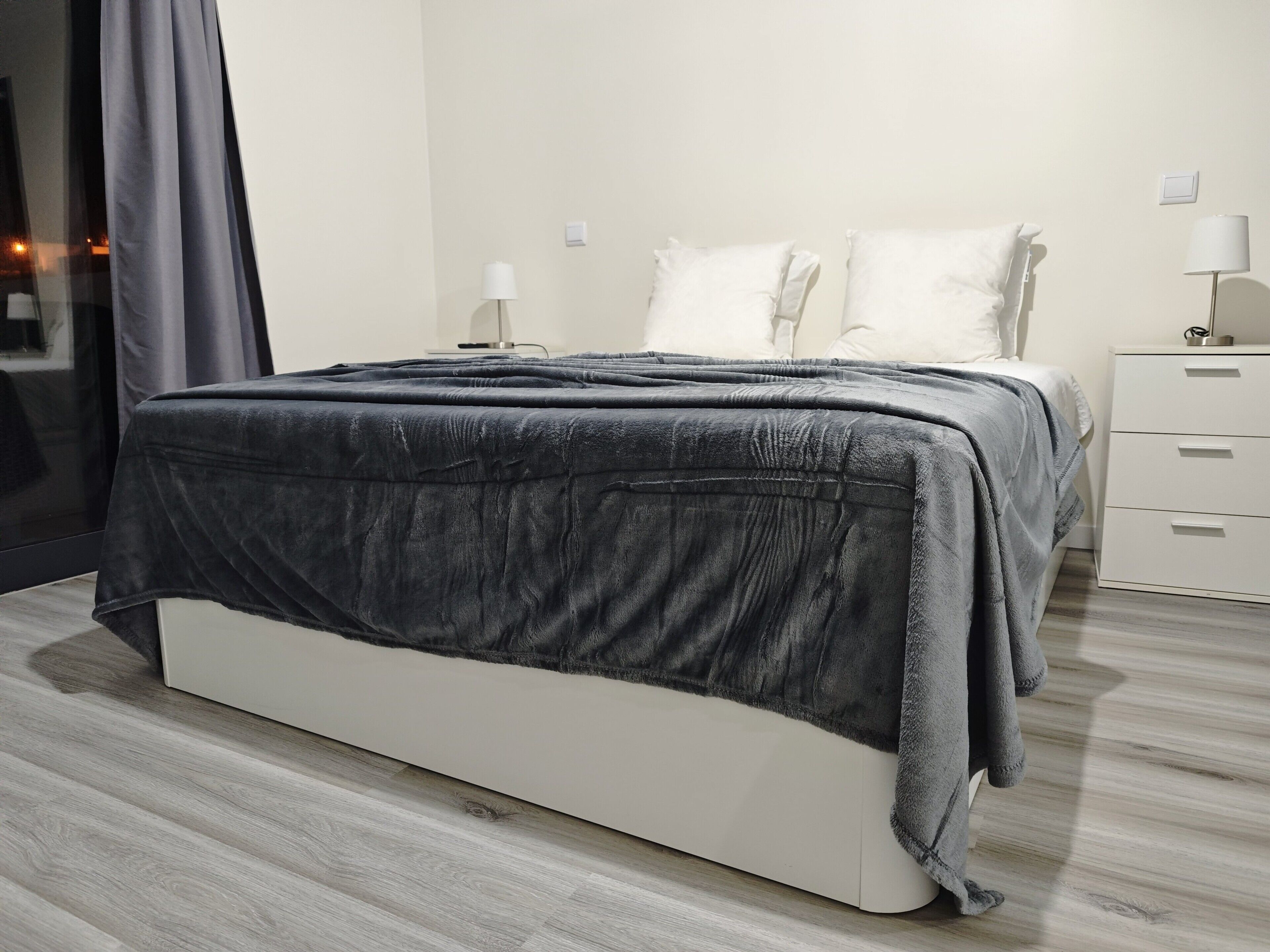 Una camera da letto moderna con un letto, comodini e un tavolino da notte.
