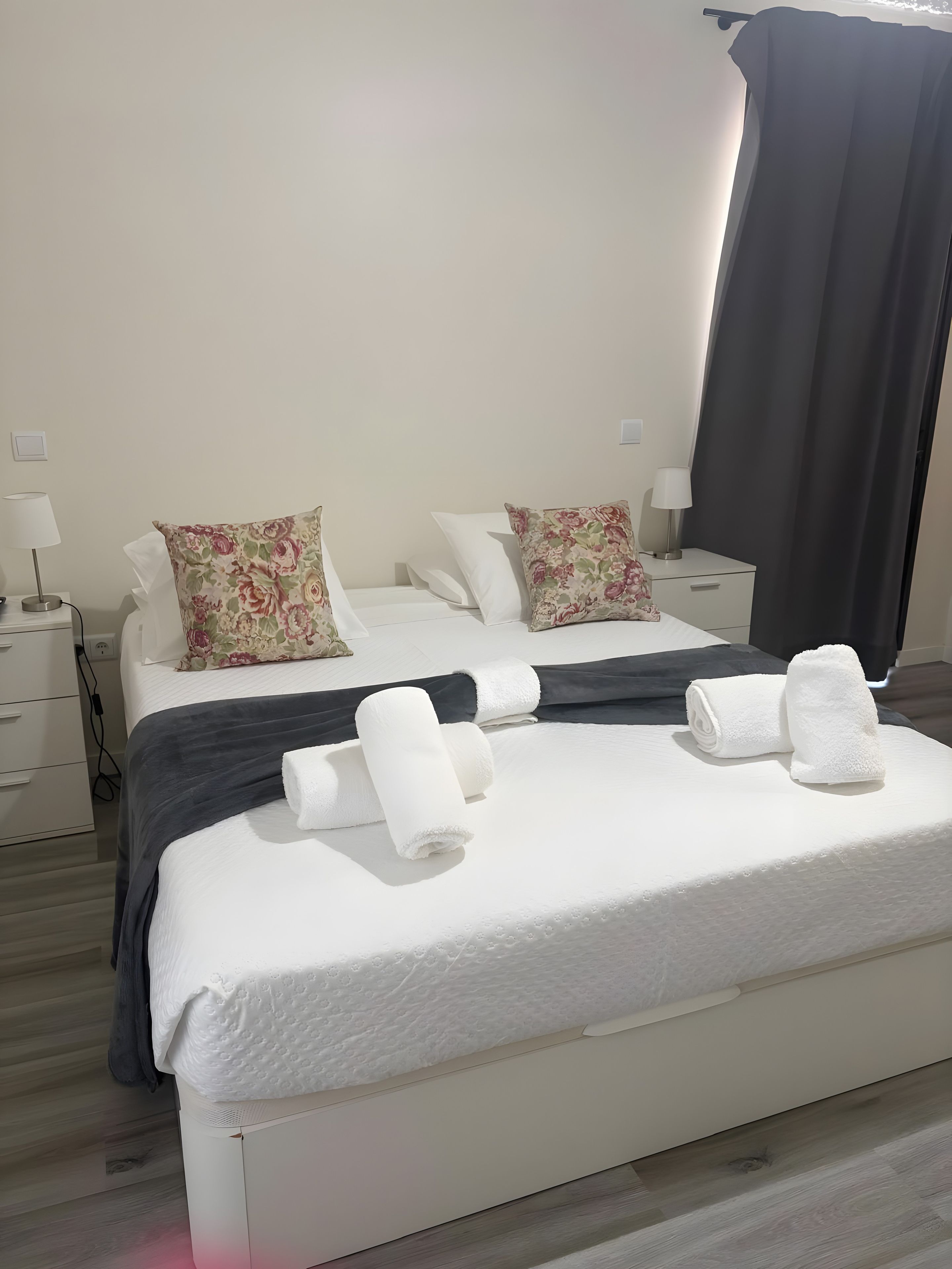 Una camera d'albergo con un letto, due comodini, una lampada e una finestra con tenda.