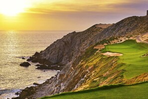 Un parcours de golf situé sur la côte, offrant une vue sur l’océan et sur le coucher du soleil.