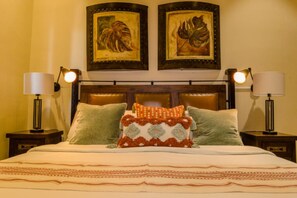 A hotel room with a bed, two nightstands, two lamps, and two framed artworks on the wall. - Quivira Luxury Penthouse | Ocean Views & Resort Amenities (Cabo San Lucas)