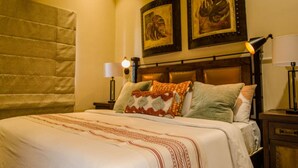 A hotel room with a large bed, two wall-mounted lamps, and two framed artworks above the bed. - Quivira Luxury Penthouse | Ocean Views & Resort Amenities (Cabo San Lucas)