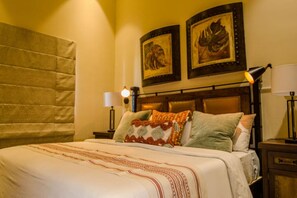 A hotel room with a large bed, two wall-mounted lamps, and two framed artworks above the bed. - Quivira Luxury Penthouse | Ocean Views & Resort Amenities (Cabo San Lucas)