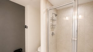 Ein modernes Badezimmer mit einer gläsernen Duschkabine, einer Toilette und einem Papierkorb.