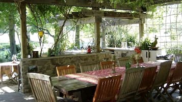 An outdoor patio with a stone wall, wooden table, and chairs.