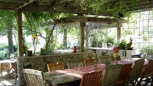 Eine Terrasse im Freien mit Steinwand, Holztisch und -stühlen.