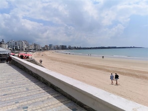 A wide sandy beach with a paved walkway along the edge. - Les Embruns - Quartier Arago (Les Sables-d´Olonne)