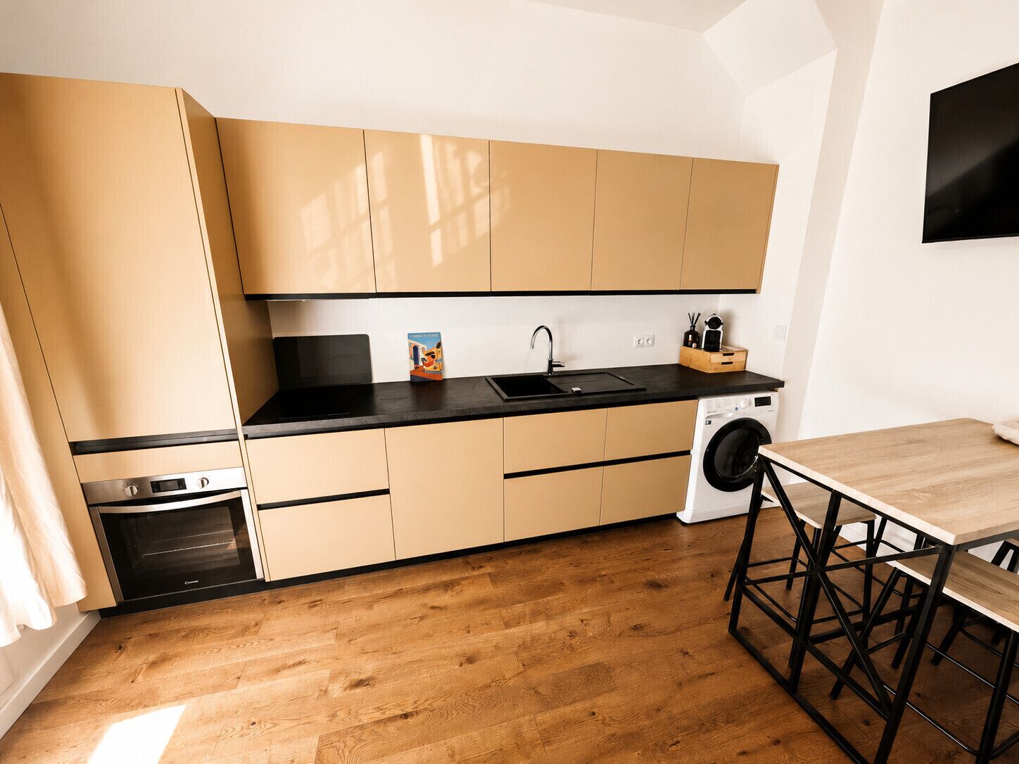 Una cocina compacta con lavadora, horno integrado y comedor con mesa y sillas.