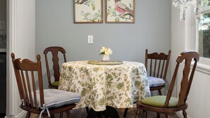 Comedor con una mesa dispuesta para cuatro personas, rodeada de sillas de madera con asientos acolchados.