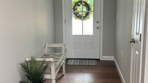 A hallway with a bench, a potted plant, a door with a wreath, and a doormat. -  Peaceful Country Getaway 3BR • 2BA • Fire Pit • Near Outdoor Adventures (Clarkrange)
