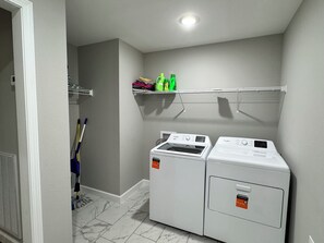 Ein Waschraum mit zwei Waschmaschinen und Trocknern von Whirlpool, einem Mop und einem Wischmop-Eimer.