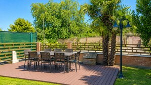 Eine Terrassengruppe mit Tisch und Stühlen, umgeben von einer Backsteinmauer und Pflanzen.