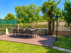 An outdoor patio with a table and chairs, surrounded by a brick wall and greenery. - Villa on the Lido of Venice, for those seeking luxury, convenience close Venice. (Venezia)