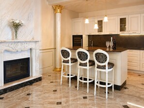 A modern kitchen with marble flooring, white cabinetry, a central island with bar stools, and a fireplace. - Villa on the Lido of Venice, for those seeking luxury, convenience close Venice. (Venezia)