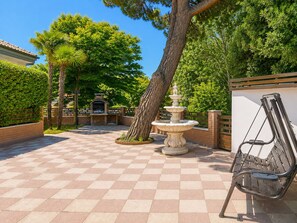 A courtyard with a checkered floor, a stone fountain, a bench, and a barbecue area. - Villa on the Lido of Venice, for those seeking luxury, convenience close Venice. (Venezia)