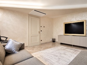 A modern living room with a sofa, a television, and a door. - Villa on the Lido of Venice, for those seeking luxury, convenience close Venice. (Venezia)