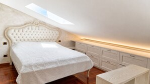 Ein Schlafzimmer mit Bett, einer Kommode und einem Oberlicht.