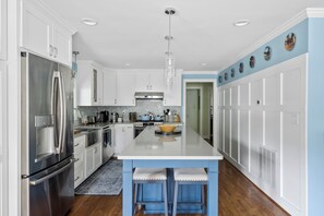 A modern kitchen with stainless steel appliances, a central island, and a blue accent wall. - Horsing around across the street from Bruce's Field. (Aiken)
