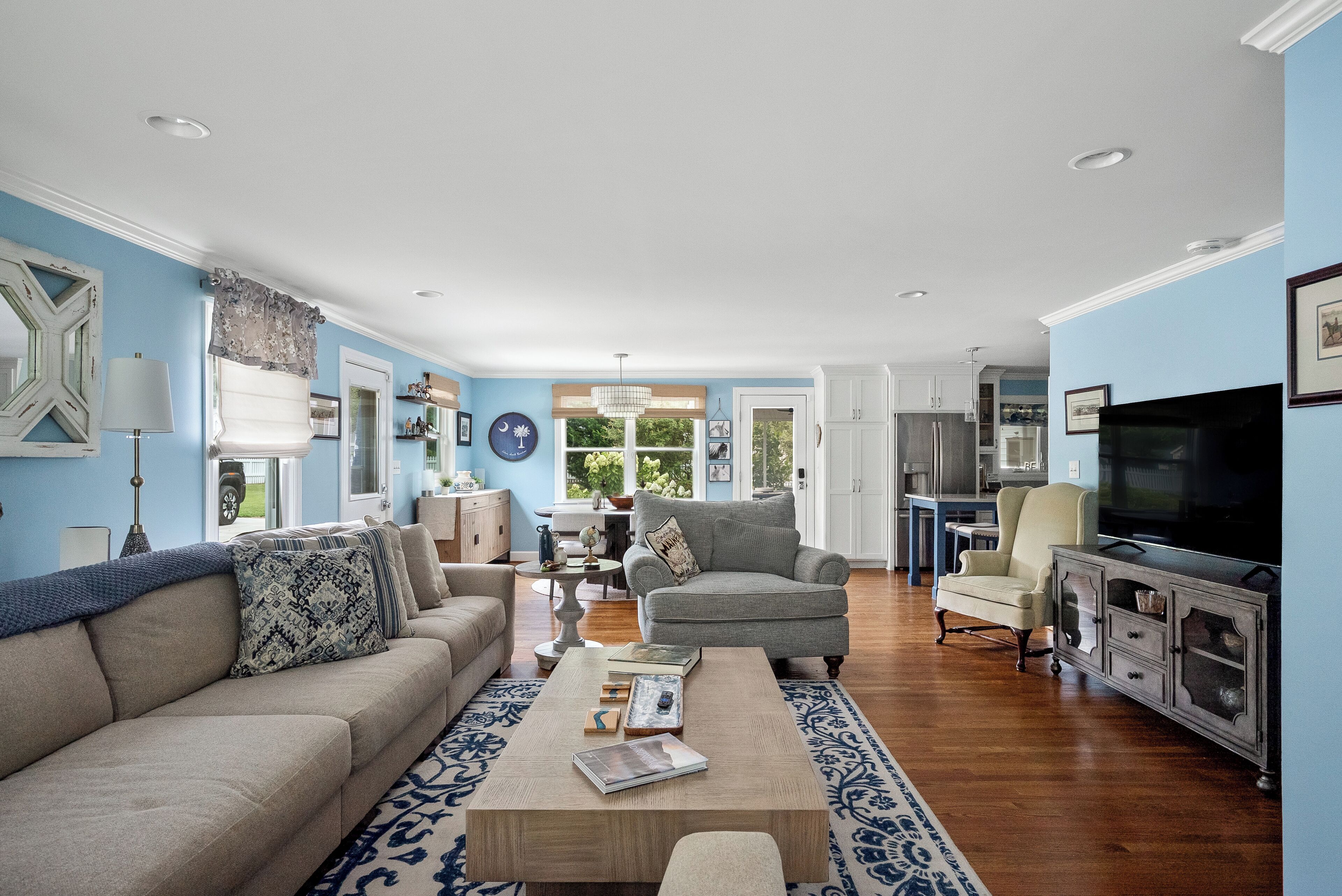 A spacious living room with a sofa, armchairs, a coffee table, and a television.