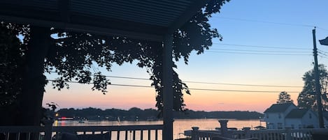 Un espace extérieur abrité offrant une vue sur une étendue d’eau au coucher du soleil.