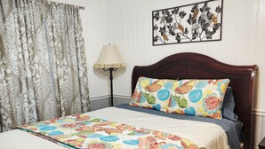 Um quarto com uma cama de madeira, um cobreleiro estampado, um quadro na parede e um abajur.