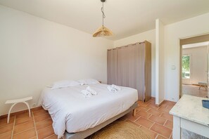 Une chambre à coucher avec un lit, une petite table blanche, un tapis tissé et un espace douche.