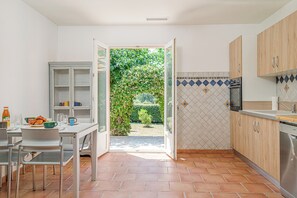 Eine Küche mit Essbereich, offene Tür zu einem Garten und einer gefliesten Spritzschutzwand.