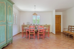 A dining area with a round table, six chairs, and a window with a view of greenery. - Maison Vigneron | Domaine Tour Campanets (Le Puy-Sainte-Réparade)