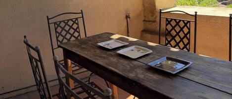 A wooden table with metal chairs on a terrace with a view of a village.