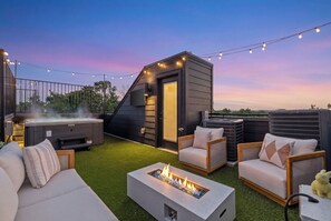 Een dakterras met buitenmeubilair, een vuurkorf en een jacuzzi.