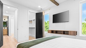 A bedroom with a bed, a TV mounted on the wall, and a window with a view of greenery. - NEW Home with Luxury Wet Room & Rooftop Hot Tub 8 to Broadway (Nashville)