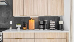 A modern kitchen with wooden cabinets, a coffee maker, a kettle, and a set of mugs. - NEW Home with Luxury Wet Room & Rooftop Hot Tub 8 to Broadway (Nashville)