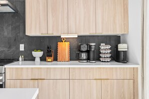 Eine moderne Küche mit Holzschränken, einer Kaffeemaschine, einem Wasserkocher und einer Kaffeetasse-Sammlung.