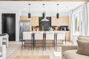 A modern kitchen with a central island, pendant lighting, and a dining area with bar stools. - NEW Home with Luxury Wet Room & Rooftop Hot Tub 8 to Broadway (Nashville)