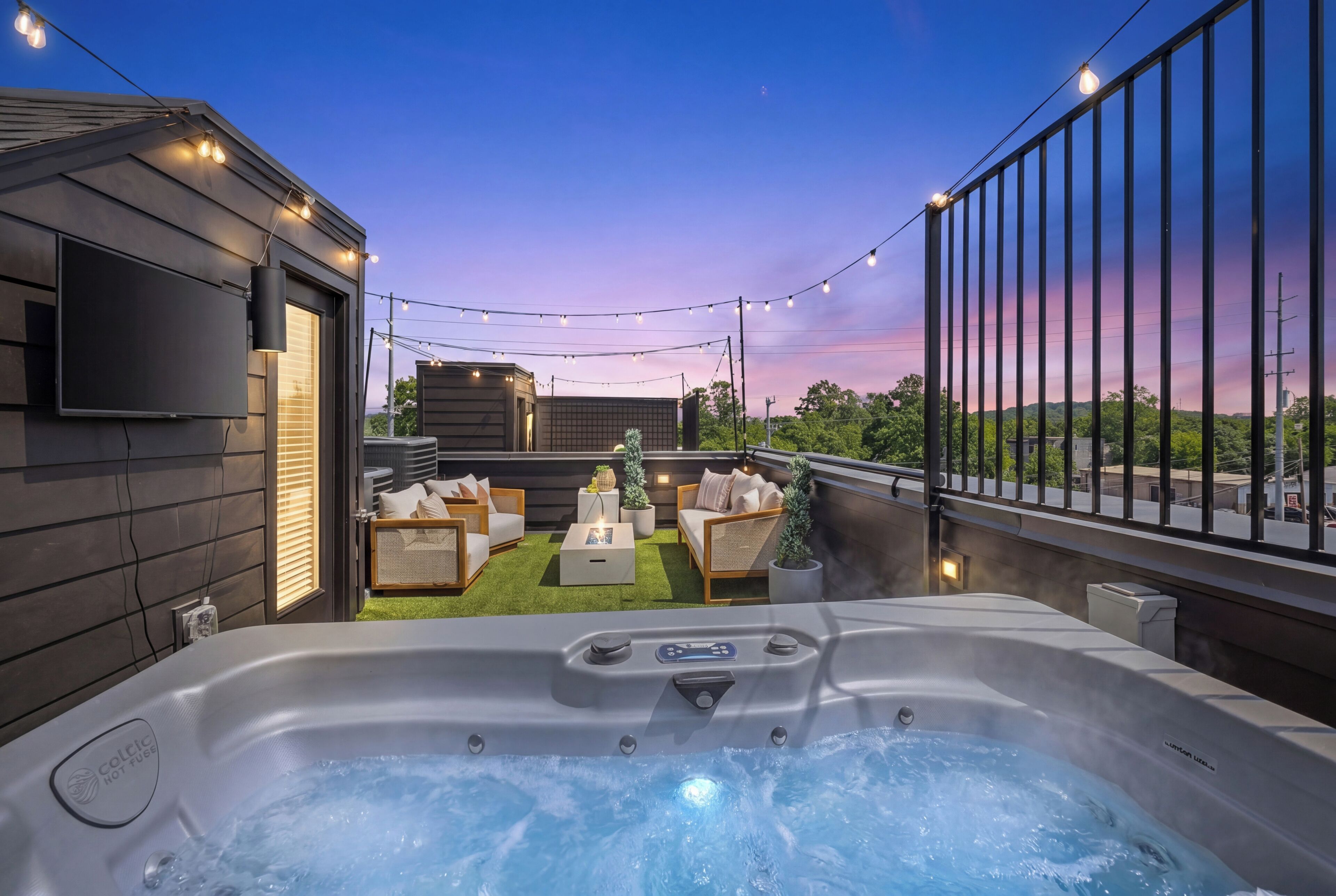 Un jacuzzi con vistas a una terraza, asientos al aire libre y un cielo al atardecer.